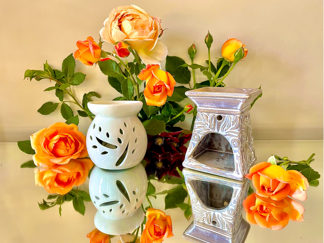 Two high quality ceramic wax burners arranged in front of a beautiful display of orange roses.