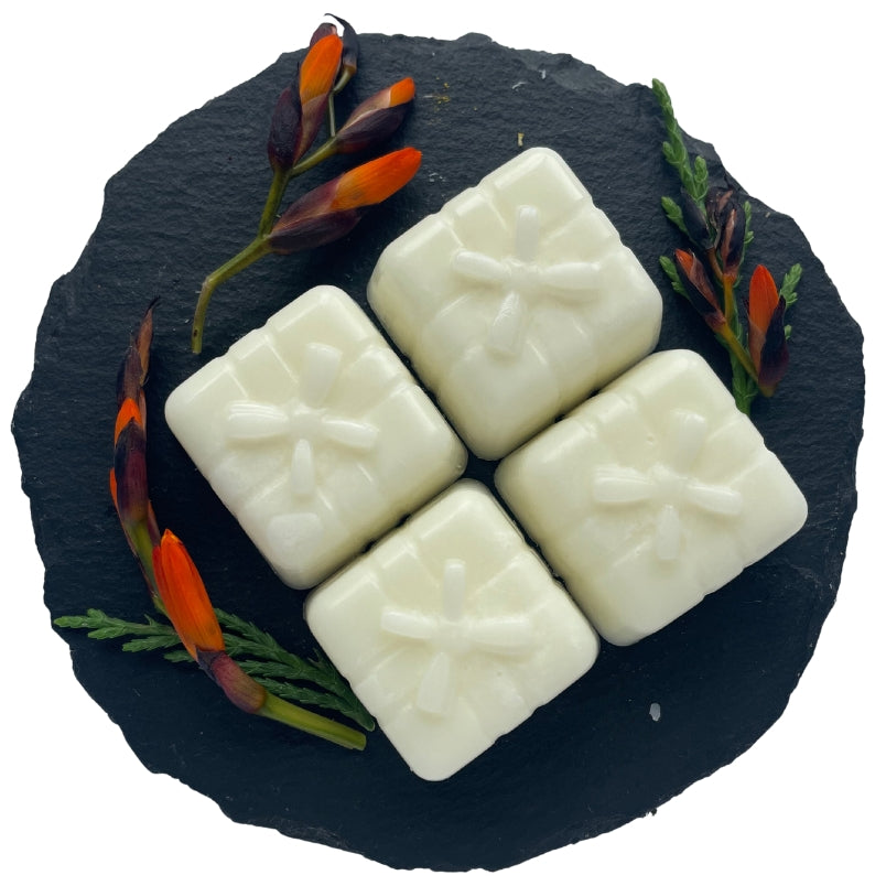 Four present-shaped wax melts on a circular slate