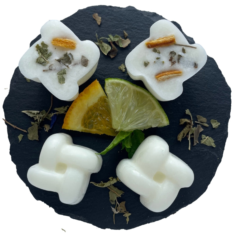 Four Lime, Basil & Mandarin wax melts on a circular slate with orange, lime and a leaf.