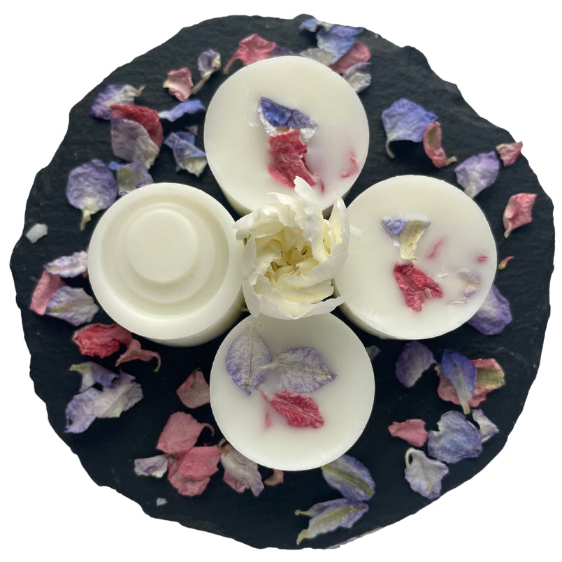 Four orange tree wax melts on a circular slate with blue and pink petals.