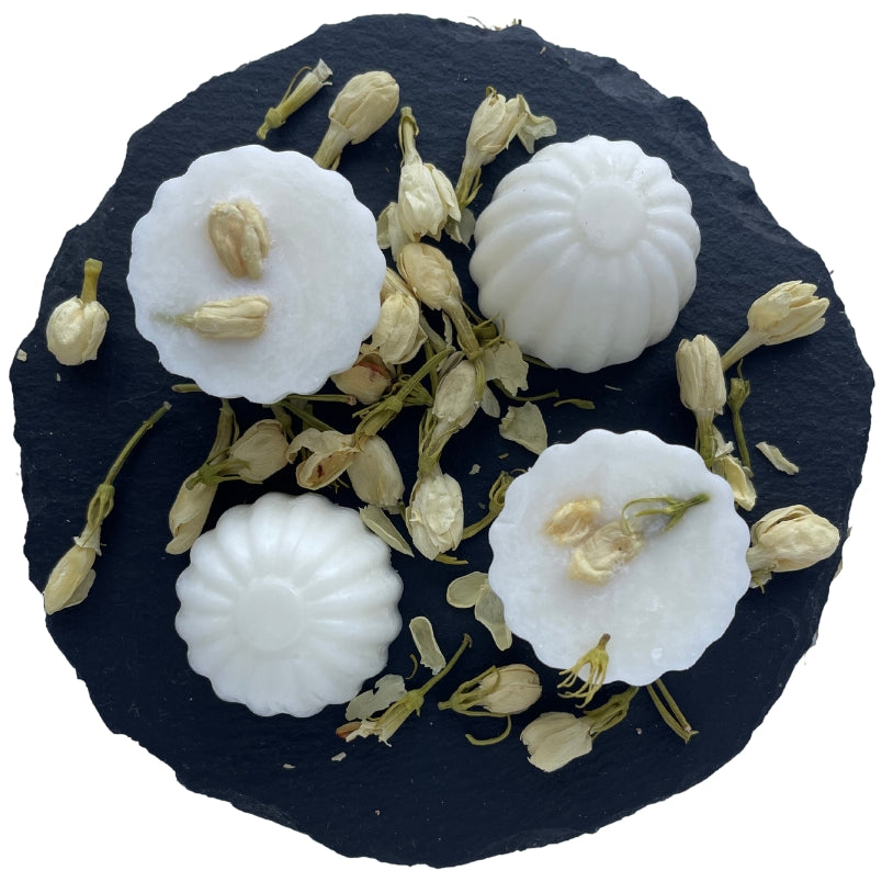 Four rhubarb and elderflower wax melts on a circular slate with white jasmine.