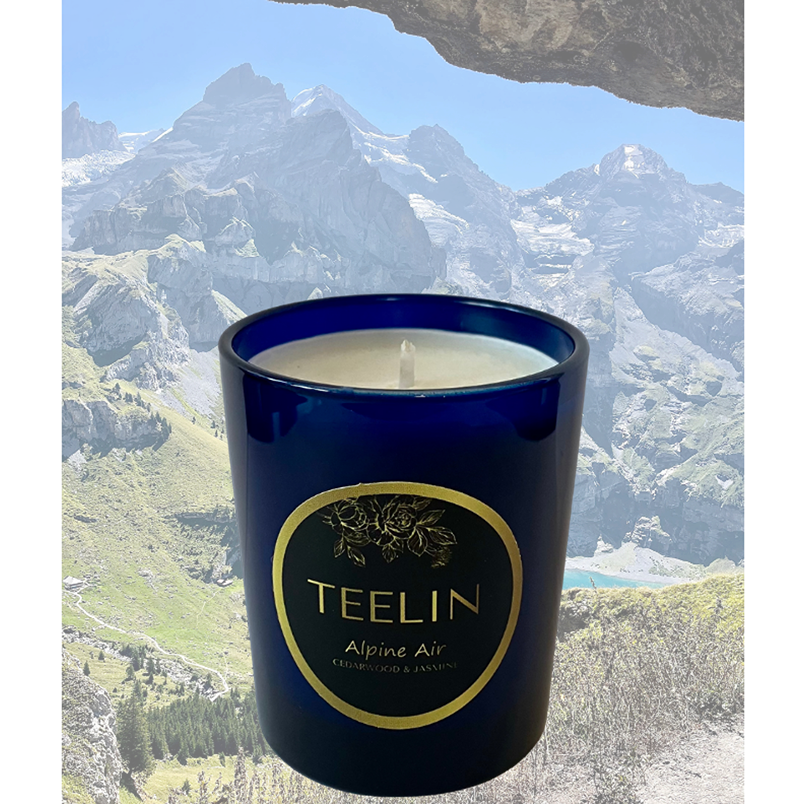 Blue sapphire candle with Teelin Luxury Fragrances label superimposed on top of a beautiful photo of a Swiss Alpine meadow valley.