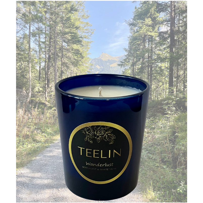 Blue sapphire candle glass with Teelin Luxury Fragrances label overlaid on top of a photo of a winding track in the beautiful Swiss Alps.